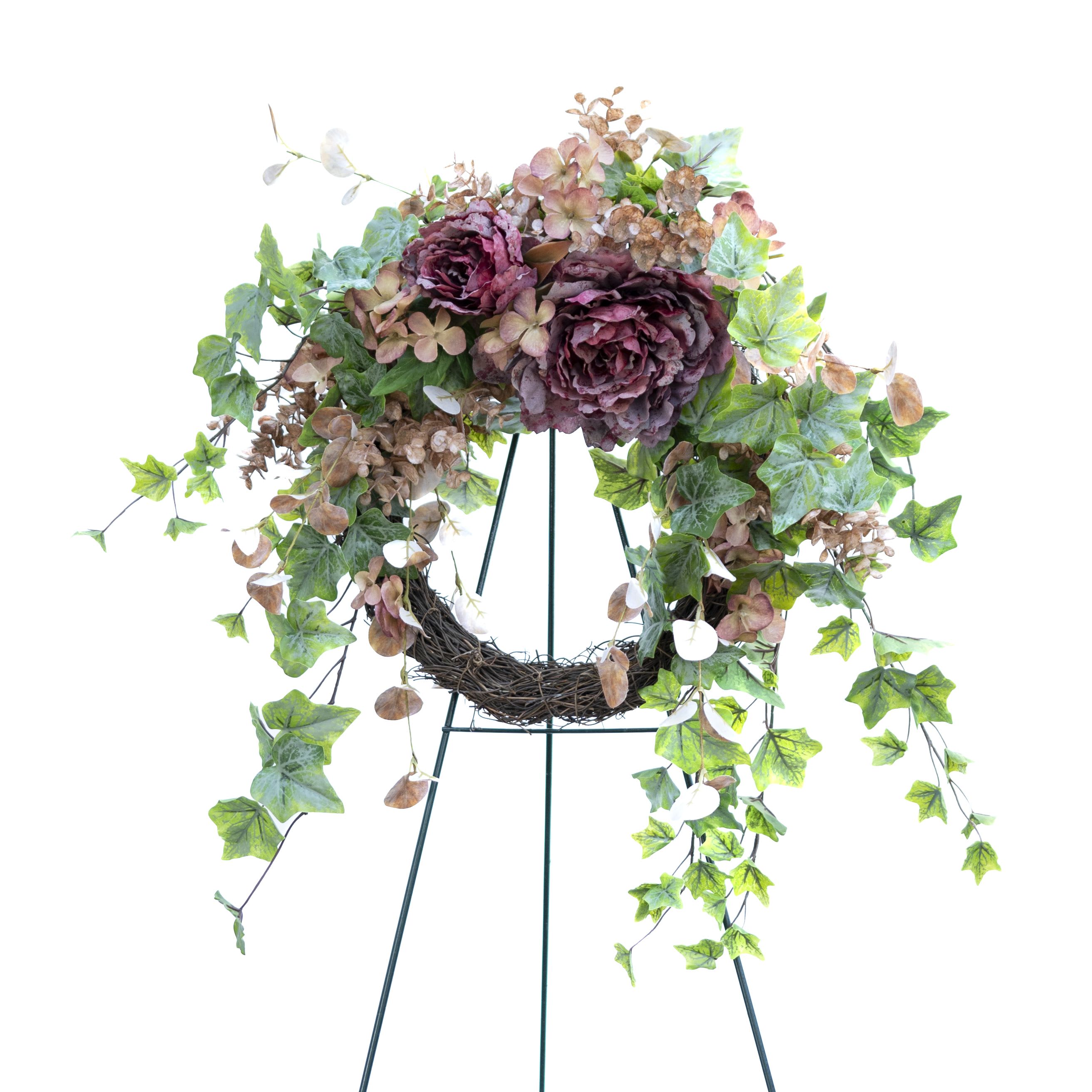 Autumn Garden Blooms Wreath- artificial - This is a beautiful artificial floral wreath featuring a combination of lush greenery and large flowers. The central elements are the richly colored, deep burgundy and faded pink roses, surrounded by delicate dried hydrangea blossoms and green ivy leaves. The wreath has a rustic base of natural vine, providing a strong yet natural foundation. Cascading greenery, including ivy and other trailing plants, adds a flowing, organic feel to the arrangement, making it ideal for display on a door or as a centerpiece for a garden-themed event.  