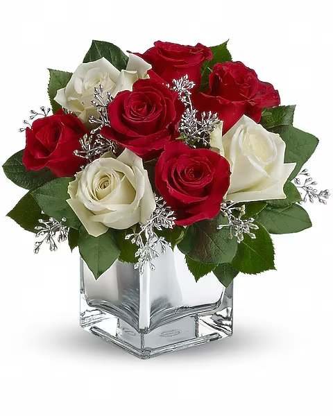 Teleflora's Snowy Night Bouquet - This exciting bouquet of red and white roses in a dazzling mirrored cube is guaranteed to make spirits brighter. Simple, stylish, affordable - better order one for yourself as well. The delightful holiday bouquet features red roses and white roses accented with assorted greenery.
