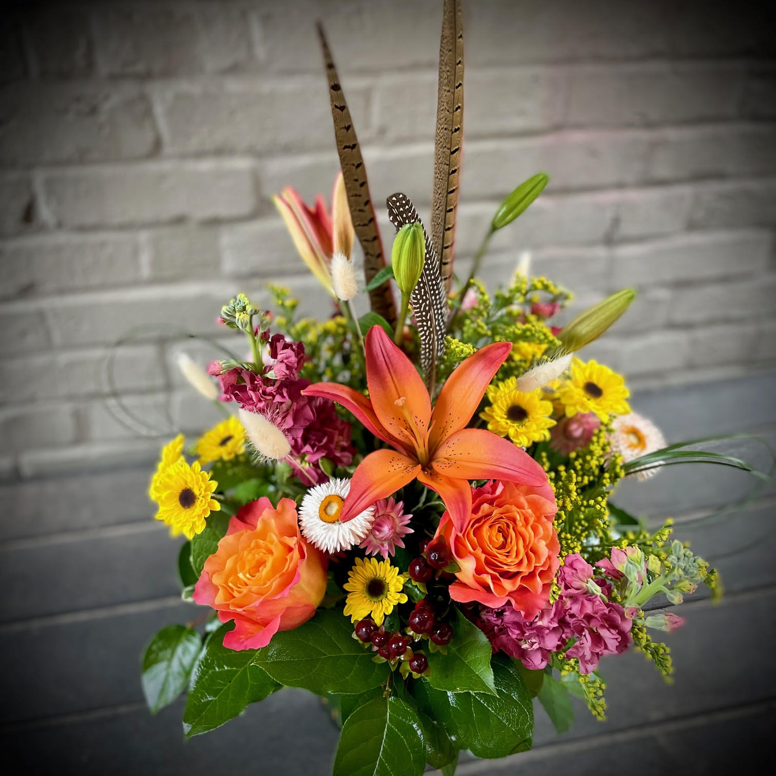 Graceful Gratitude - Share your thanks with the Graceful Gratitude design. Composed of lilies, roses, stock, mums, and strawflower, this array of oranges, mauve, and yellows brings warmth and cheer to any home or office space. Approximately 15 inches by 15 inches.