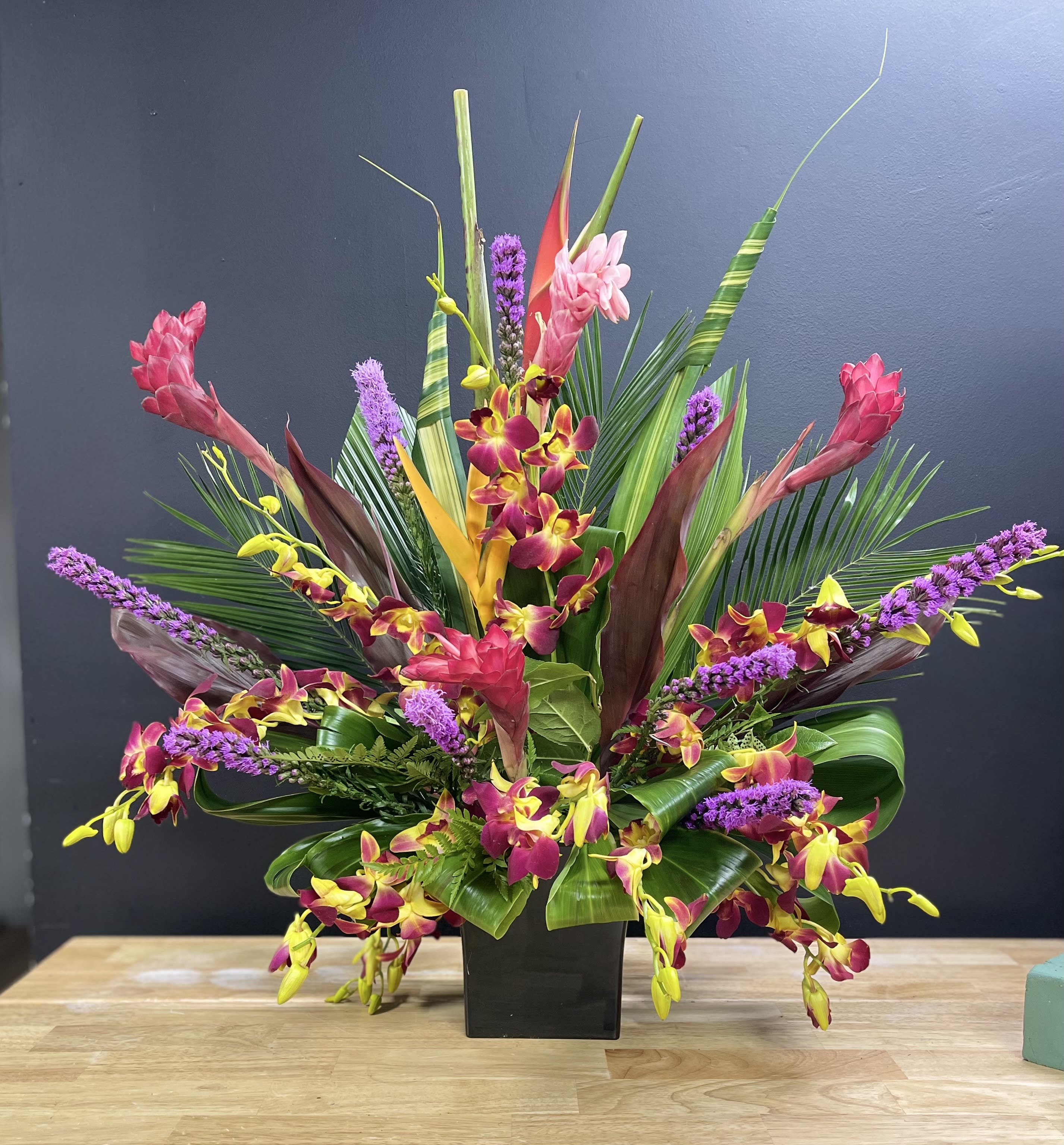Madi Gras in hawaii -  A burst of colors tied in to a beautiful Arrangement.   SUBSITUTION POLICY In many instances, our photo may represent an overall theme or look and include a one-of-a-kind vase which cannot be exactly replicated.  Although the actual bouquet may not precisely match the photo, its temperament will. Occasionally, substitutions of flowers and/or containers happen due to weather, seasonality and market conditions which may affect availability. If this is the case with the gift you’ve selected, we will ensure that the style, theme and color scheme of your arrangement is preserved and will only substitute items of equal value or higher value.  If any design elements are of major importance to your order, please include them in the florist instructions at checkout or contact us to ensure availability.  