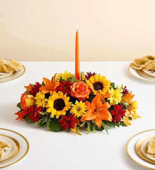 Autumn centerpiece  - All-around arrangement with autumn-colored roses, sunflowers, red daisy poms, orange Asiatic lilies; accented with assorted greenery and dried oak leaves