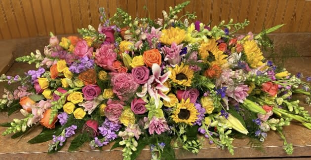 Sophia's Everlasting Casket Piece - A full celebration of colors, this multi-flower and bright casket spray is representative of a life lived to its fullest. Standard choice will be presented as pictured. Deluxe and Premium will include more flowers. 