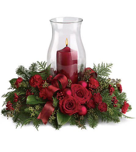 Holiday Glow Centerpiece - Glow ahead and send this spectacular centerpiece to anyone who's on your Christmas list this year. A glowing hurricane candle takes center stage but the surrounding festive touches make this arrangement radiate joy. Beautiful red roses spray roses and carnations white asiatic lilies festive Christmas greenery and ornaments plus an elegant hurricane candle make this divine Christmas d?cor.Approximately 19&quot; W x 15 1/2&quot; H Orientation: All-Around As Shown : T115-3ADeluxe : T115-3BPremium : T115-3C