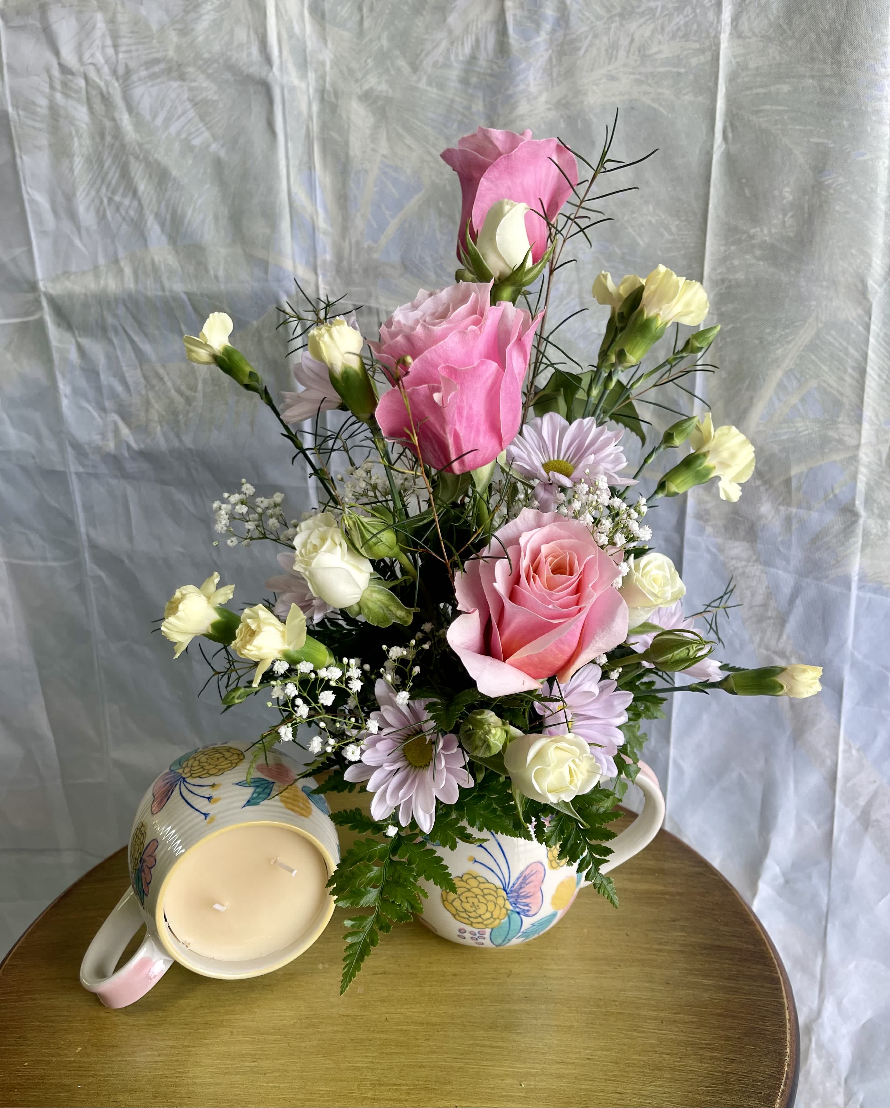 Grace - With Sweet Grace fragrance and an uplifting message, 3 gifts in one! A mug filled with a candle in the ever so popular Sweet Grace fragrance is topped with a lovely set of fresh blooms. We have pictured this beautiful arrangement with a mug candle to give you a look at what's under the floral arrangement pictured. (Flower colors may vary. All designs are arranged as similar as possible. We promise to keep the same color, style, and overall theme with what Mother Nature generously blesses us with)
