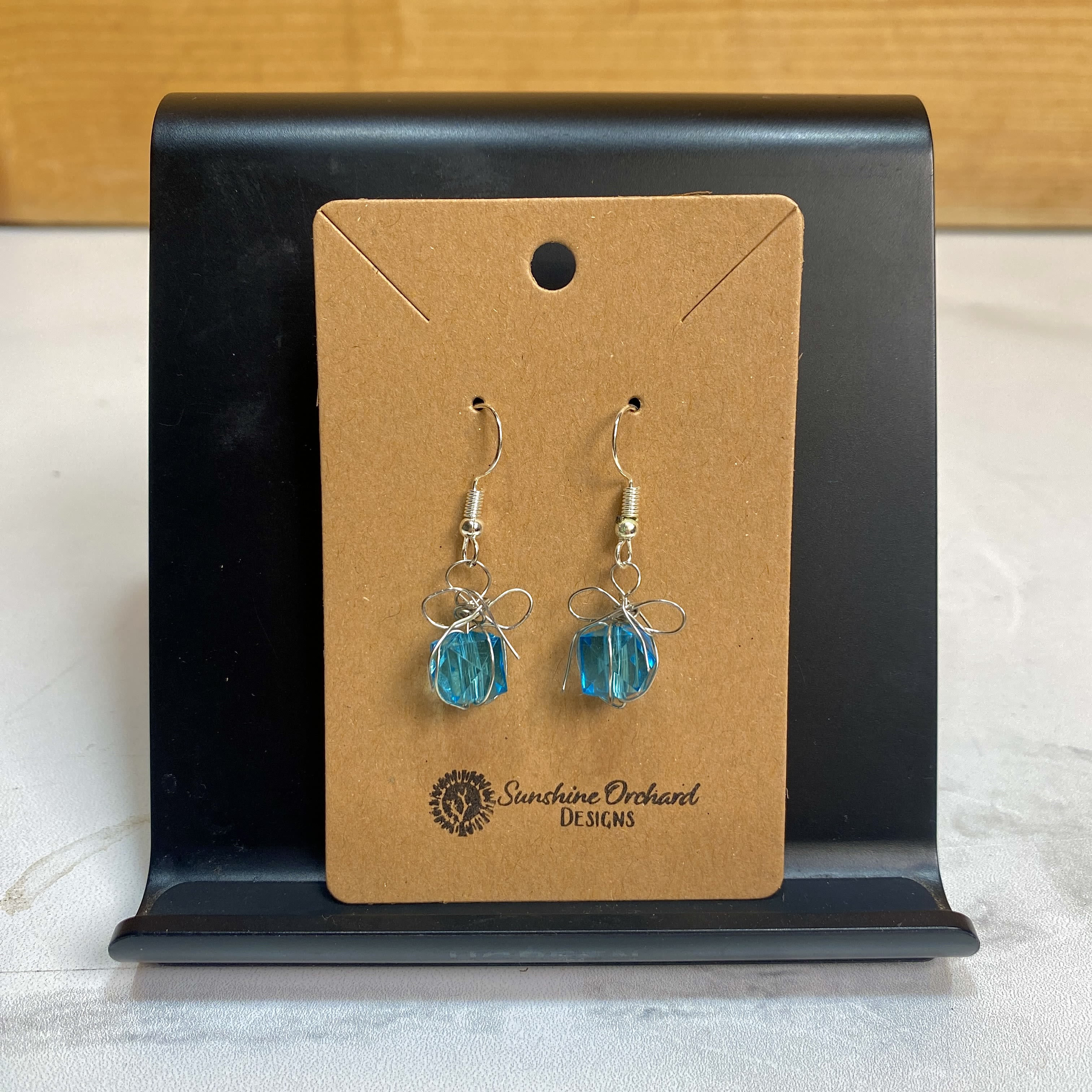 Blue Present Earrings - These Blue Present Earrings are absolutely adorable, and a great way to get into the spirit of the season! Handmade out of acrylic beads with silver wire making up the bow of the present, this pair of earrings is simple but stylish! Earrings handmade by Sunshine Orchard Designs