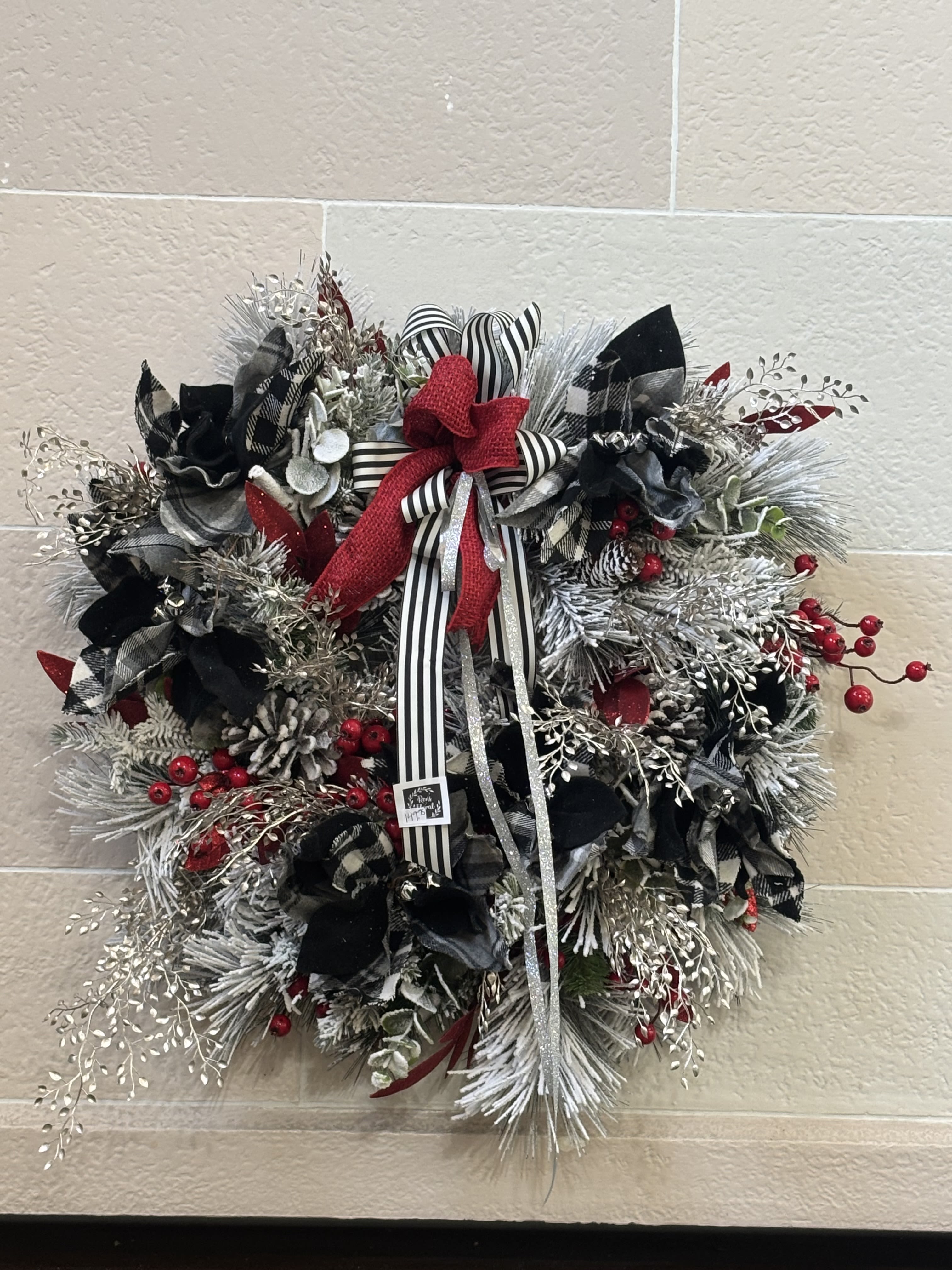 Black and White Wreath  - A frosted pine wreath filled with silver accents,  black and white poinsettias, berries, and a bow. 