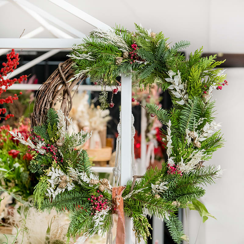 Evergreen Winter Wreath - Decorate your home with this beautiful Forever Holiday Wreath. Arranged with mixed evergreen foliage such as spruce, fir, and pine, and pops of unique dried flowers, this wreath is long lasting, full of texture and style in shades of whites, reds &amp; gold accents.  Copper Velvet Ribbon to accent. (18&quot;)