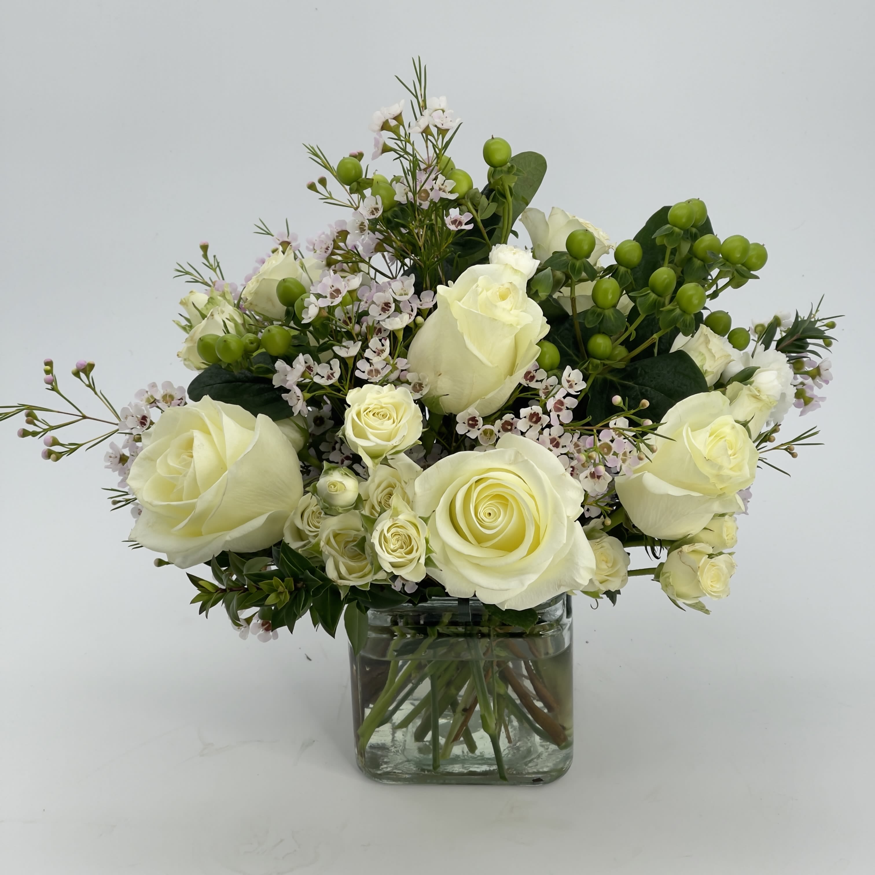 Wonderfull White Bouquet - A White bouquet of White Roses, White spray roses, wax flowers and green coffee beans in a cube glass vase.