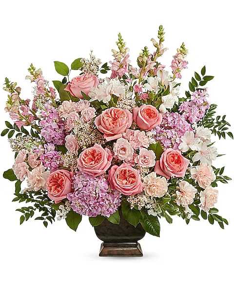 Teleflora's Feeling Loved Bouquet - A truly amazing arrangement for any beloved occasion, this radiant rose bouquet in a classic footed urn is an expression of eternal love. This arrangement includes pink hydrangea, pink roses, pink spray roses, ivory alstroemeria, light pink carnations, pink snapdragons, pink stock, white sinuata statice, pink waxflower, huckleberry, lemon leaf and variegated pittosporum. Delivered in a Noble Heritage Urn.