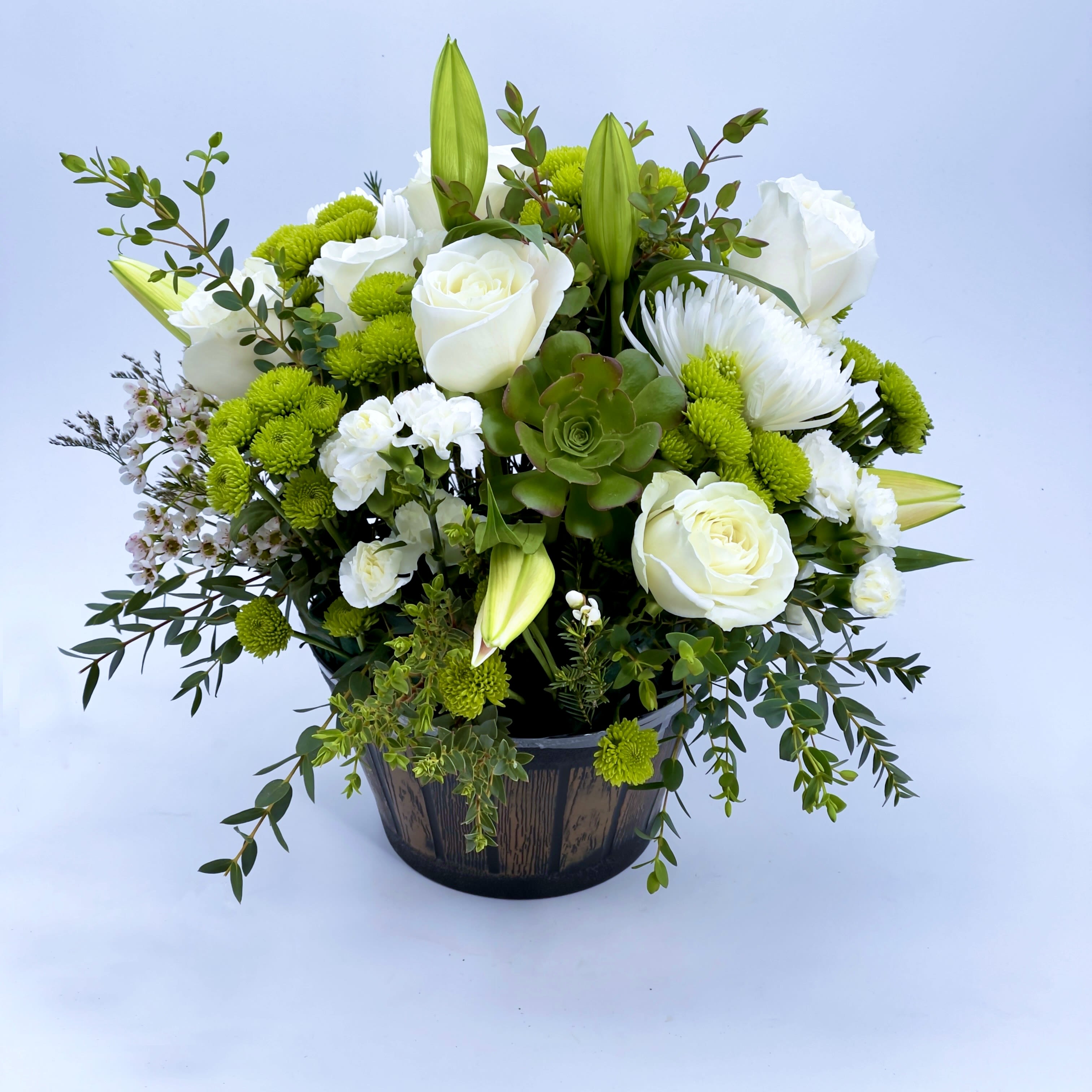 Winter White Bouquet - A fresh and elegant arrangement featuring white roses, lilies, and green accents, beautifully arranged in a rustic wooden container. Perfect for adding a touch of natural charm and serenity to any space.
