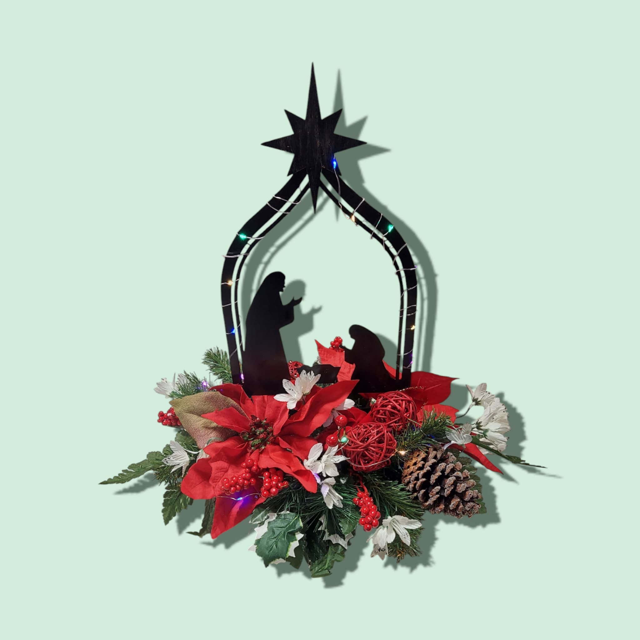 Away In A Manger- *ARTIFICIAL FLOWERS - A metal silhouette nativity scene, wrapped in timer lights, is beautifully displayed among artificial greenery and Christmas blooms. Approximate size: 18&quot;H  x 17&quot;W