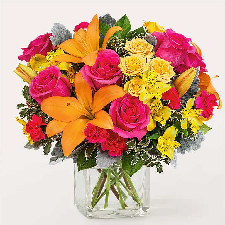 Harvest Bloom - “Bring joy and energy to any occasion with this vibrant and colorful bouquet! Featuring bold orange lilies, hot pink roses, sunny yellow spray roses, and cheerful alstroemeria, this arrangement is bursting with life. Accented with lush greenery and arranged in a modern clear glass vase, it’s the perfect centerpiece to brighten someone’s day or celebrate a special moment with a splash of color. ”