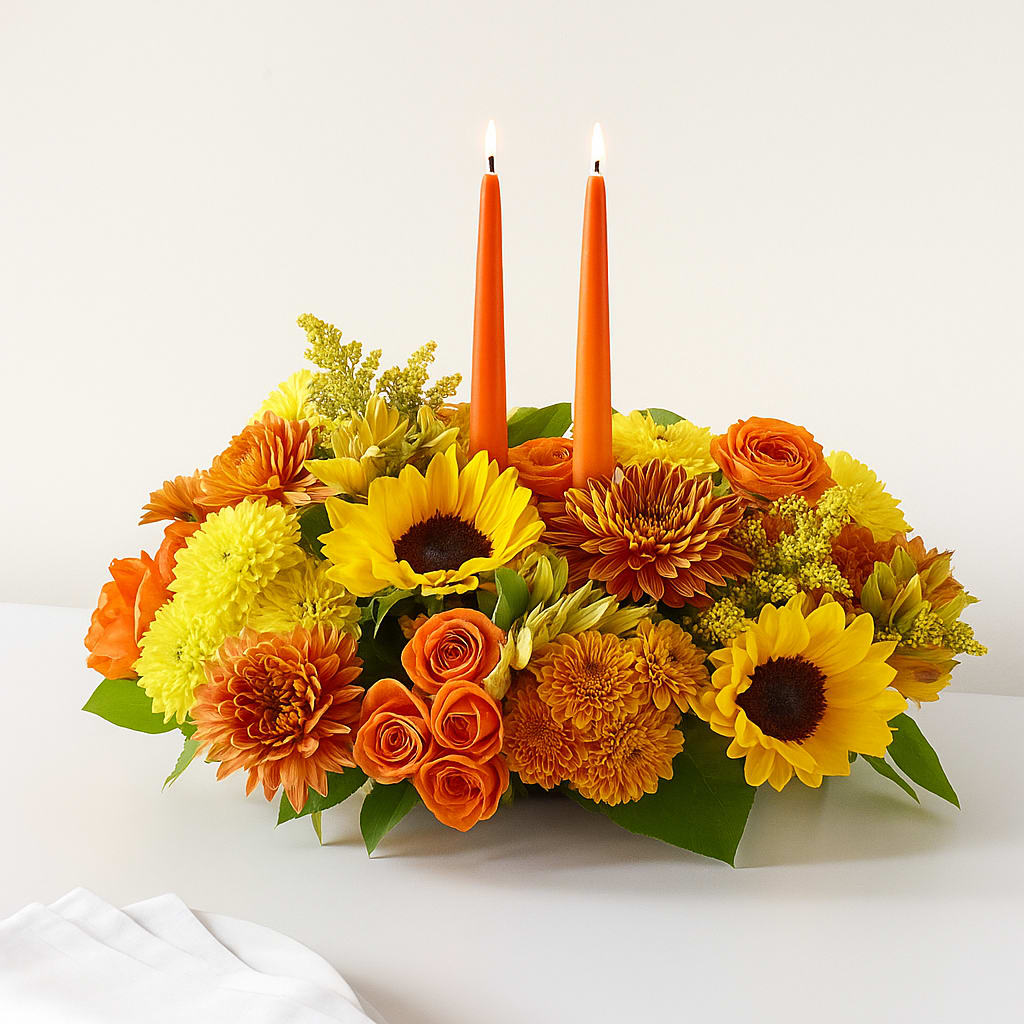 Autumn Candlelight Gathering  - Warm sunflowers, amber mums, and glowing roses come together around twin taper candles that rise like gentle beacons. This centerpiece captures the feeling of friends gathering at a fall table—soft light, shared comfort, and the warmth of the season resting in every petal.