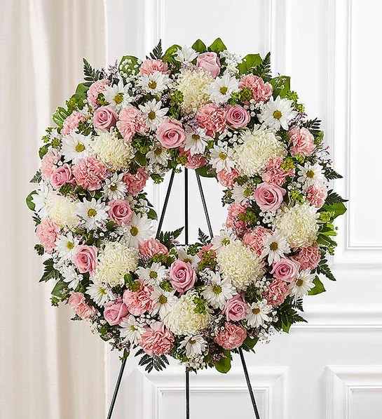 Serene Blessing Pink &amp; White - The memories shared with a loved one can help bring serenity after they are gone. Our standing wreath in pink is a lovely way to celebrate those moments. Expertly crafted by our local florists with graceful pink and white blooms for a lush, full presentation, this traditional funeral arrangement is a beautiful way to honor their life.