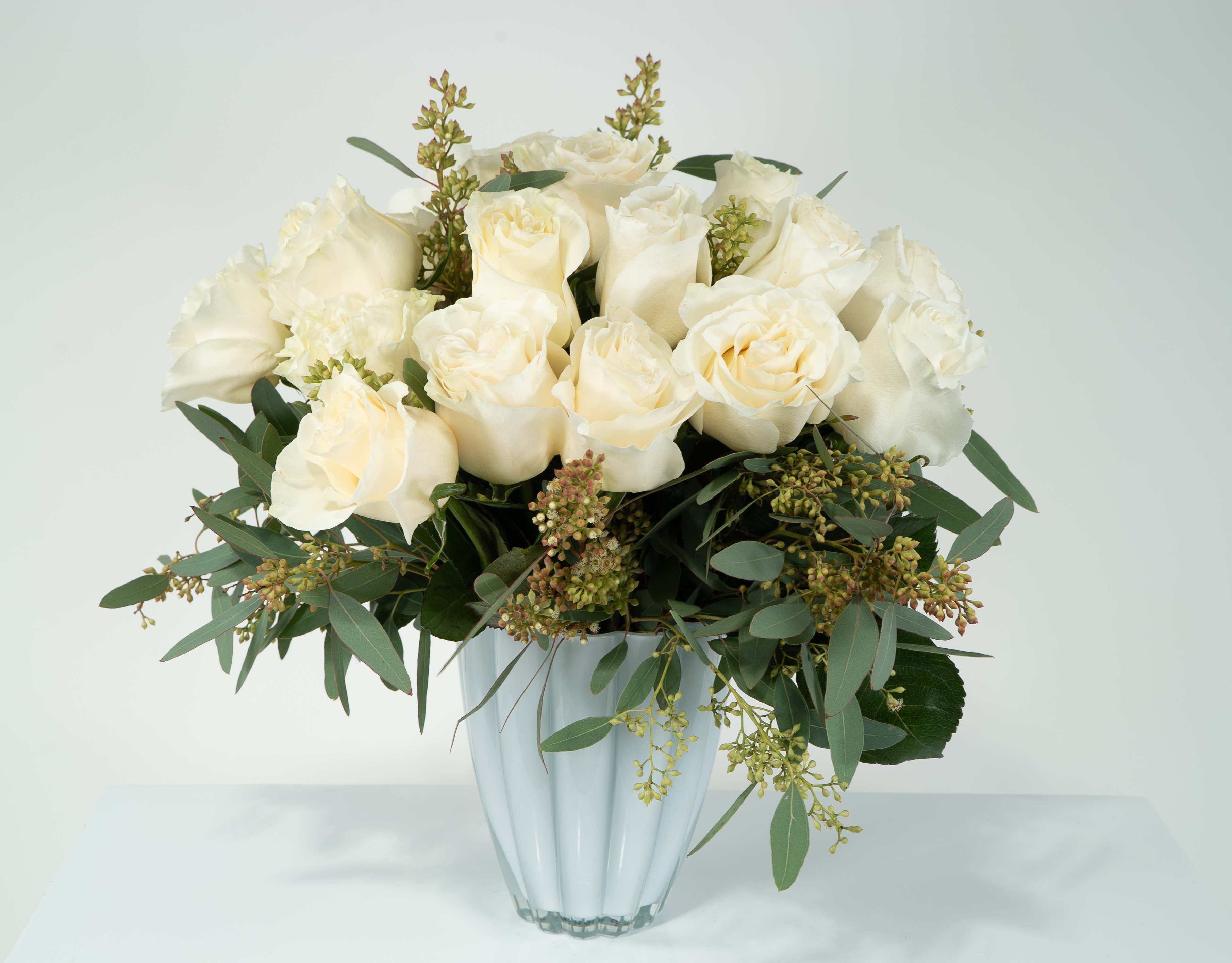 Cinderella  - These 2 dozen white roses with seeded eucalyptus in our flower shaped vase were made for a princess. This is a true fit of love. 
