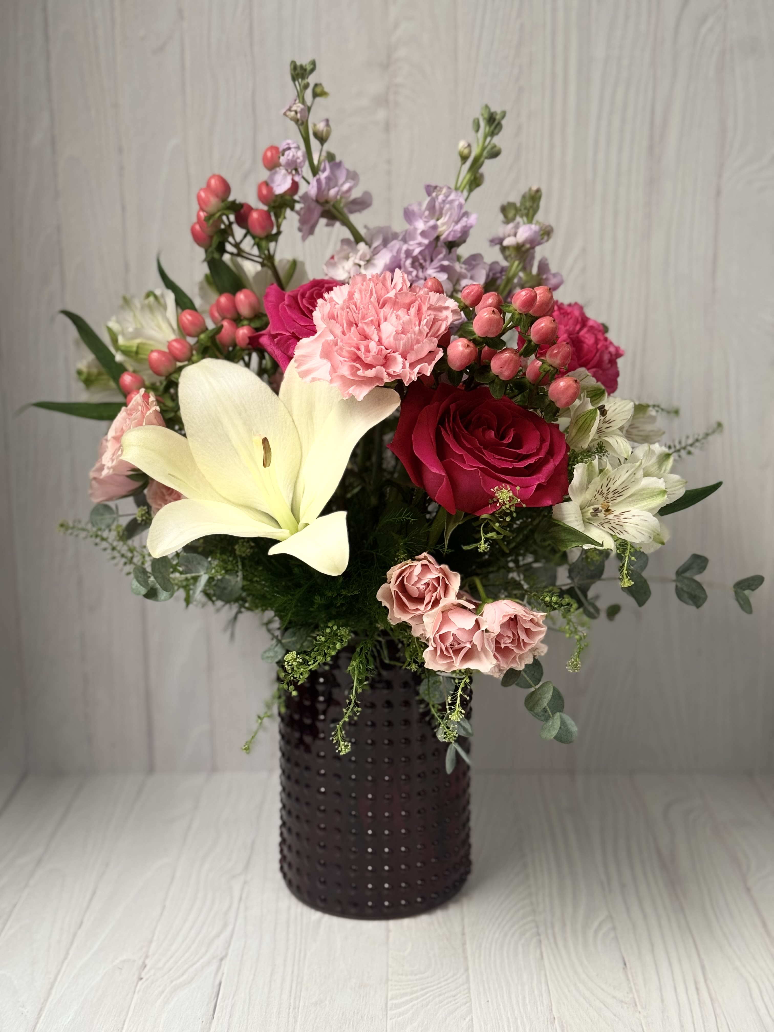 Pink Passion - All the favorites in a trendy colored vase with Roses, Stock, Cushion Mums, Lily and premium filler &amp; greenery.  We will do our best to make as PINK as possible for your recipient that loves all shades of pink!