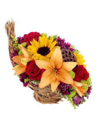 Fall Cornicopia Arrangement - The Cornucopia Flower Centerpiece is inspired by the classic cornucopia design, but filled with flowers instead of fruit. The Fall flowers in the centerpiece include sunflowers, orange lilies, red roses and green pots. Artfully created by hand this florist delivered bouquet can be delivered today to your home or to friend's home.