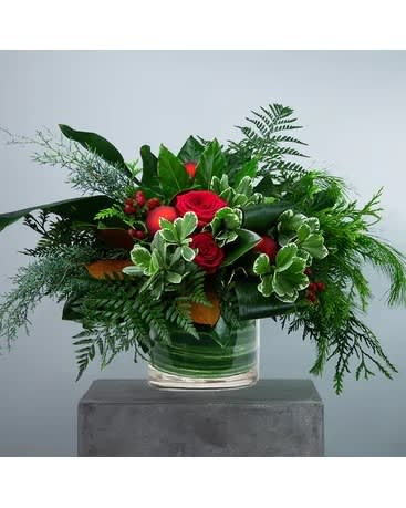 Unending Joy - Add warmth and wonder to any room. Unending Joy brings the alluring colors and smells of winter in. A clear glass cylinder container features an abundance of mixed foliage like magnolia, aroma pine, arborvitae, pittosporum, leather leaf, and aspidistra. Approximately 30&quot; W X 19&quot; H   All prices in USD ($)  DGTMF-1251