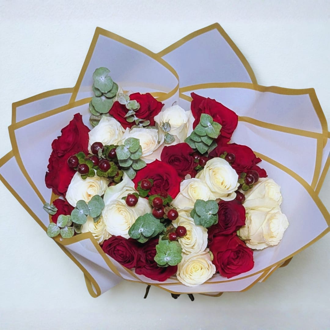 Harmony Rose Wrap - A beautiful hand-tied bouquet featuring 24 premium red and white roses, accented with baby blue eucalyptus and rich burgundy hypericum for a festive, romantic finish. Wrapped in our signature white-and-gold paper for a refined presentation.