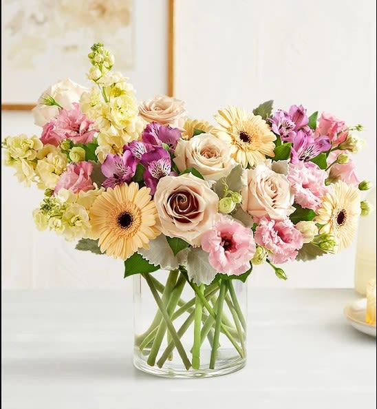Nature's Charm - Our charming bouquet displays nature’s beauty at its most serene and inviting. The loose, stylized arrangement, in a soft palette of pink, peach, and cream, is gathered in a glass cylinder vase and makes a refreshing surprise for every moment.