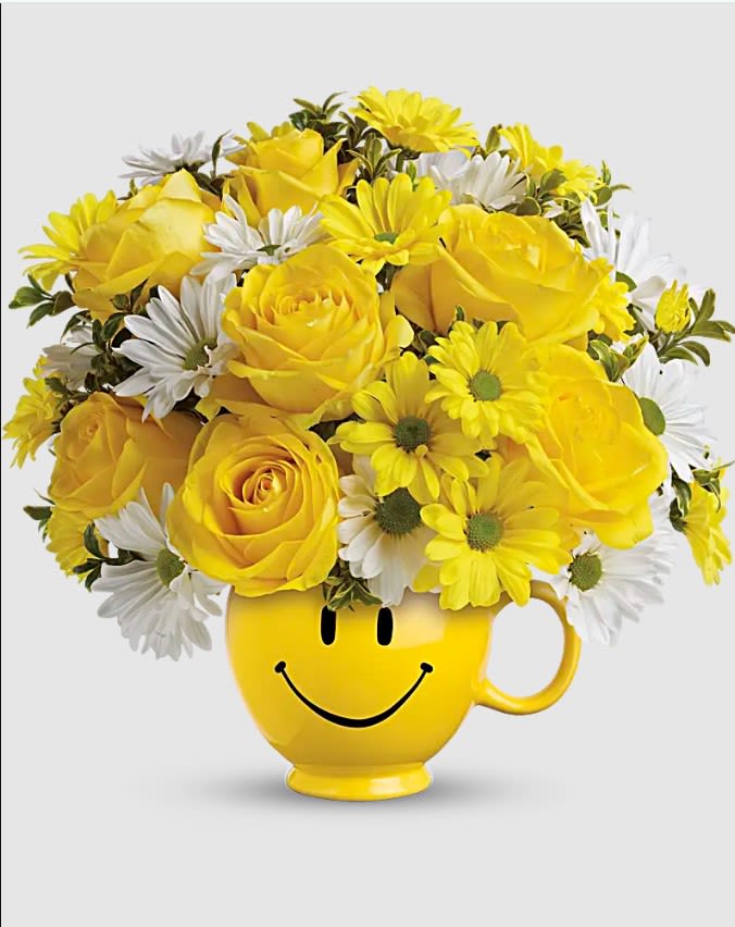 Teleflora's Be Happy Mug - When you're looking to make someone smile, this happy face mug of roses and daisies is tops. Sure to cheer up everyone from a beloved wife to a busy boss, these are also great flowers for kids. Yellow roses and daisy spray chrysanthemums along with white daisy spray chrysanthemums and oregonia are delivered in Teleflora's one and only yellow happy face, Be Happy® mug.. Orientation: One-Sided