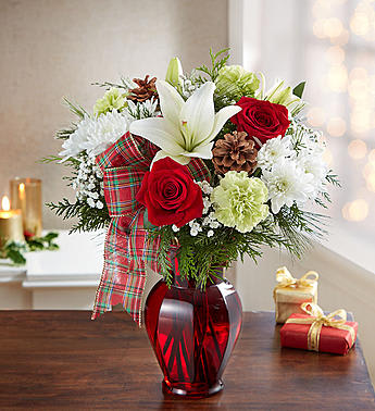 161260 HOLIDAY TIDINGS BQT - •All-around arrangement with red roses; white Asiatic lilies and cushion poms; lime green carnations; baby’s breath and assorted greenery; accented with pinecones and decorative plaid ribbon