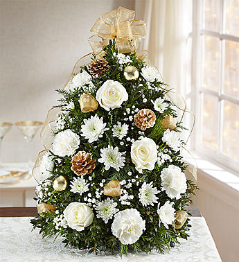 GLISTENING GOLD HOLIDAY FLOWER TREE - •Tree-shaped arrangement with white roses, cushion poms and carnations; assorted greenery; baby’s breath; accented with gold ornament balls, pinecones and a gold bow topper