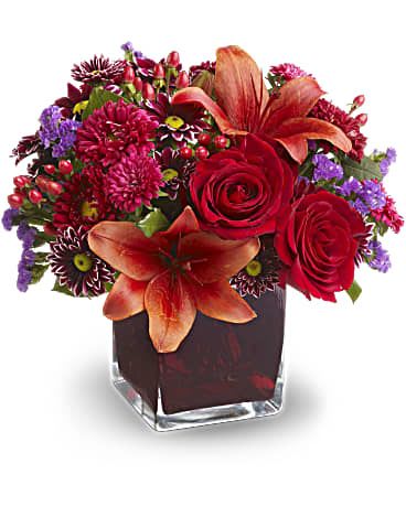 Autumn Grace - Roses, lilies and asters in precious gemstone colors of garnet are nestled into a richly colored plum glass cube vase, creating a graceful presentation. Purple chrysanthemums and seafoam statice add a special touch. A beautiful bouquet for any occasion! Red roses, Asiatic lilies, Matsumoto asters and hypericum; purple daisy spray chrysanthemums and seafoam statice are delivered in a plum glass Teleflora cube vase. Orientation: All-Around