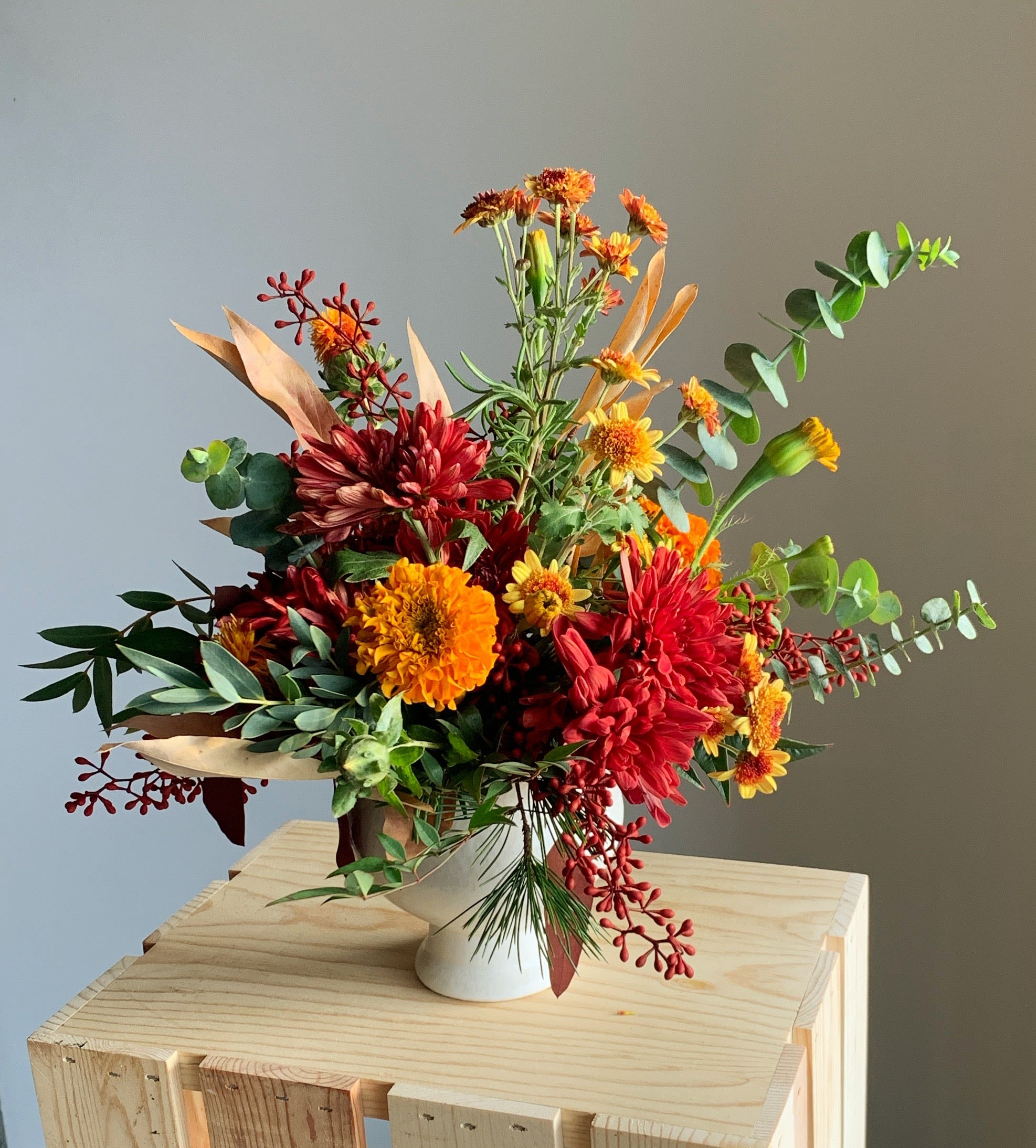Thanksgiving Centerpiece - Adorn your holiday table with the warm shades of autumn. Filled with seasonal heritage chrysanthemums, berries, everlasting leaves &amp; a touch of fragrant rosemary this centerpiece add the final touch to your decor. Each arrangement is creatively designed in a creamy ceramic compote. 