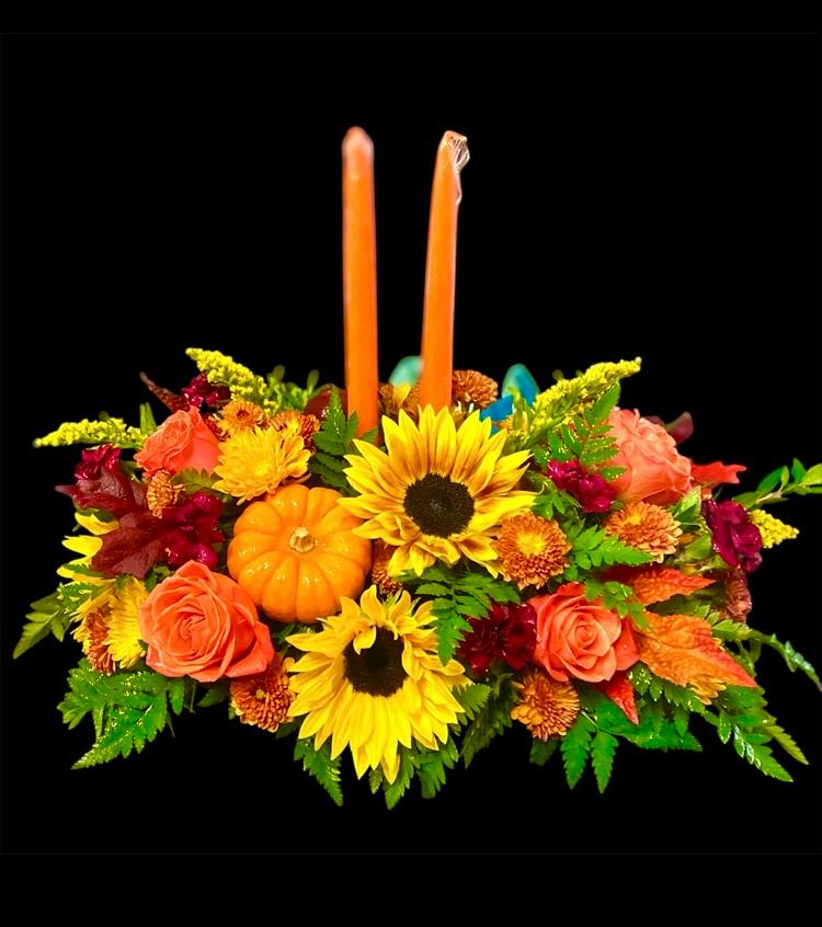 Sunflowers &amp; Thanksgiving   - This traditional centerpiece includes a wonderful variety of Fall colors and blooms. Composed of Sunflowers, Roses, Alstroemeria, Carnations, various fall Mums, and various fall foliage. This centerpiece is accented with fresh mini Pumpkins and topped off with two tapered candles. This design measures approx. 24&quot;W x 9&quot;H (not including candles). 