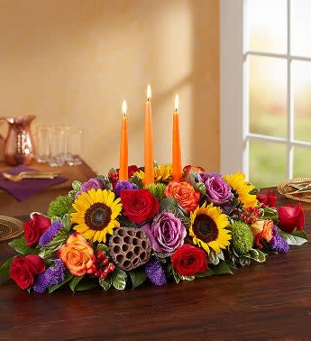 Garden of Grandeur for Fall - Autumn gatherings call for a grand centerpiece. We’ve designed our luxurious arrangement with a mix of brightly-colored blooms and unique, textural accents, creating a truly unique table display. A trio of orange candles provides the perfect finishing touch for spirited celebrations.