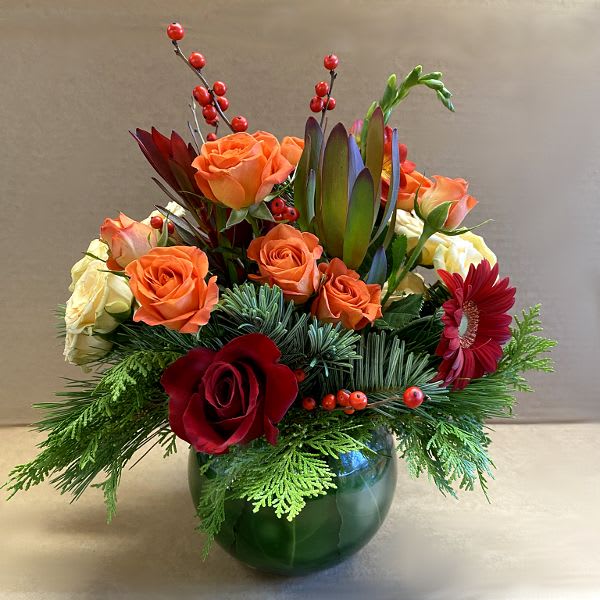Spiced Wine - As a festive spiced wine for the holidays, the palette for this floral arrangement celebrates warm spicy tones such as rich reds, orange and creamy peach. A unique and modern color combination of roses, gerberas, leucadendron, freesia, winterberry and seasonal evergreens.