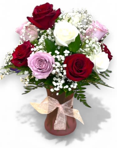 Premium One Dozen Rose Vase Arrangement - This elegant rose vase arrangement features a stunning dozen mixed roses in a variety of beautiful, soft hues, creating a harmonious blend that exudes charm and sophistication. The roses are thoughtfully complemented by lush filler flowers, adding texture and fullness to the display. Nestled amidst a bed of fresh, verdant mixed greens, the arrangement highlights the natural beauty of each bloom. Presented in a premium, clear glass vase that radiates elegance, it is finished with a graceful bow tied around the neck, adding a charming touch of refinement. Whether for a special occasion or to brighten any space, this arrangement radiates beauty, elegance, and heartfelt sentiment.  