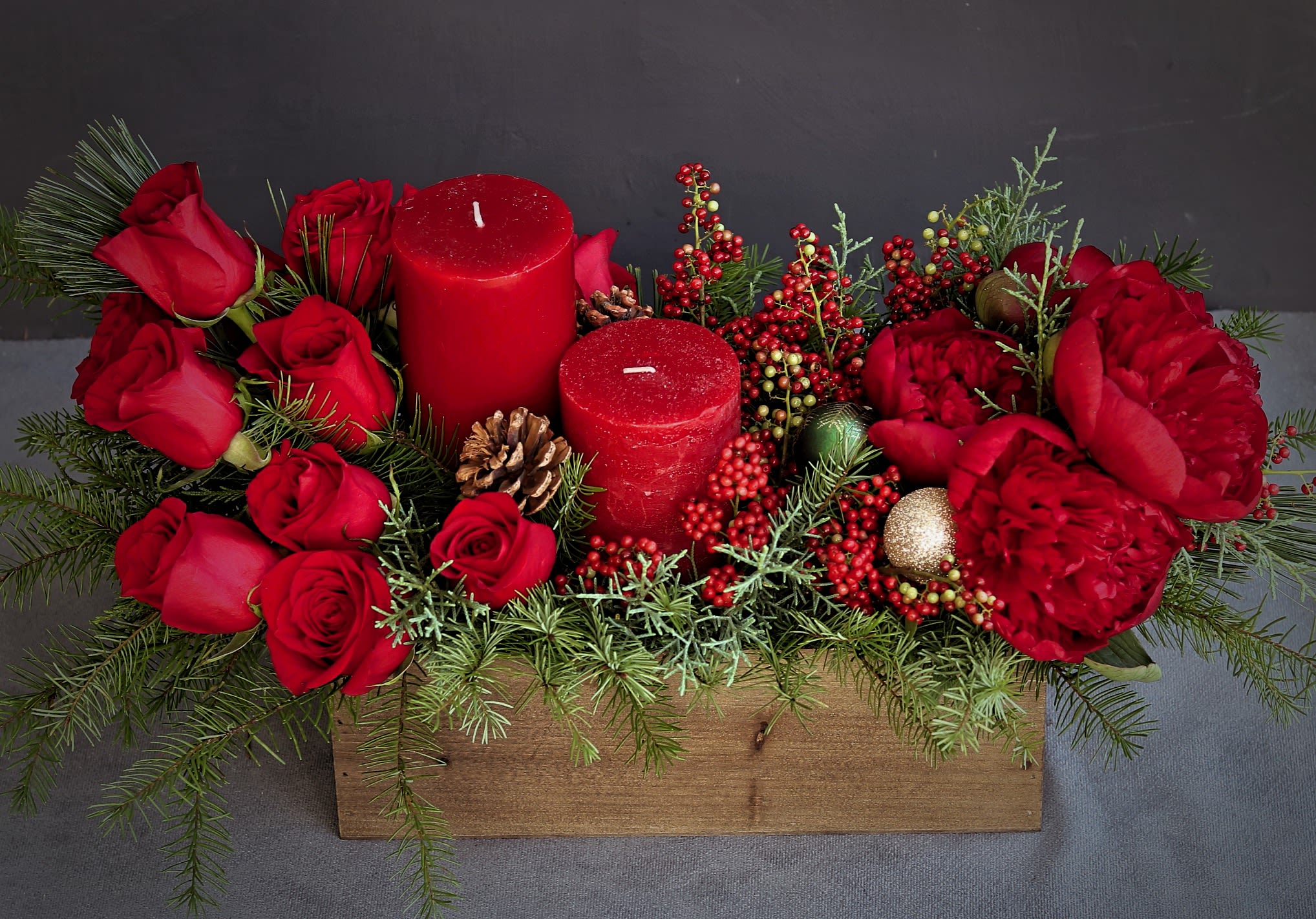 christmas centerpiece with candles - Red flowers and candles with Christmas berries, greens, pinecones and ornaments in a  rectangular wooden box. Greeting card with a handwritten message is included. Send the most beautiful flowers for that special someone. Same day delivery available to Tequesta, Jupiter, Palm Beach Gardens and Palm Beach.