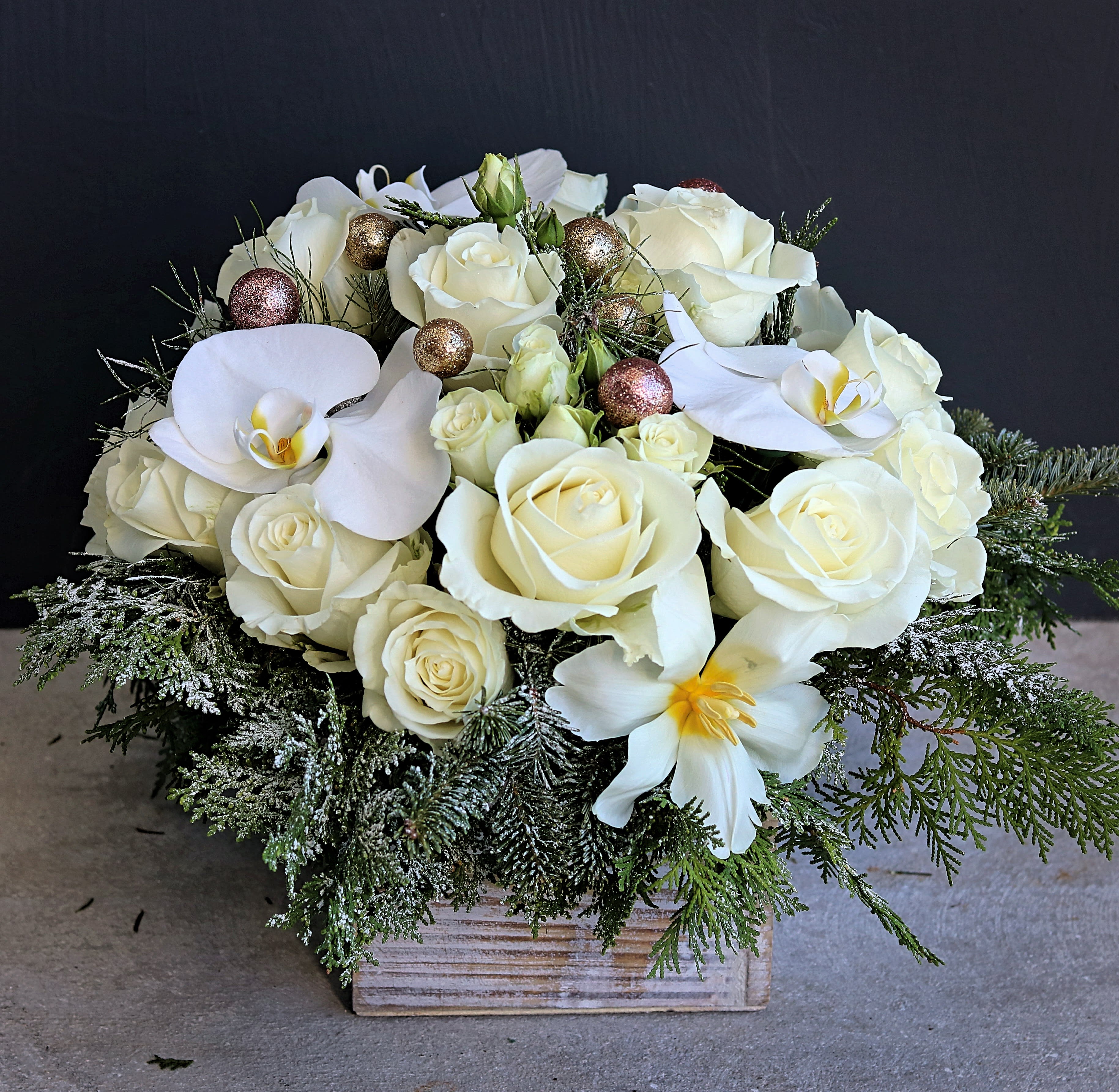 christmas centerpiece with orchids - This Christmas centerpiece contains premium blooms such as peonies, roses, tulips, orchids and others surrender with Christmas greens covered in faux-snow. It's in a 5&quot; square wooden planter. Next day delivery available to Tequesta, Jupiter, Palm Beach Gardens and Palm Beach.