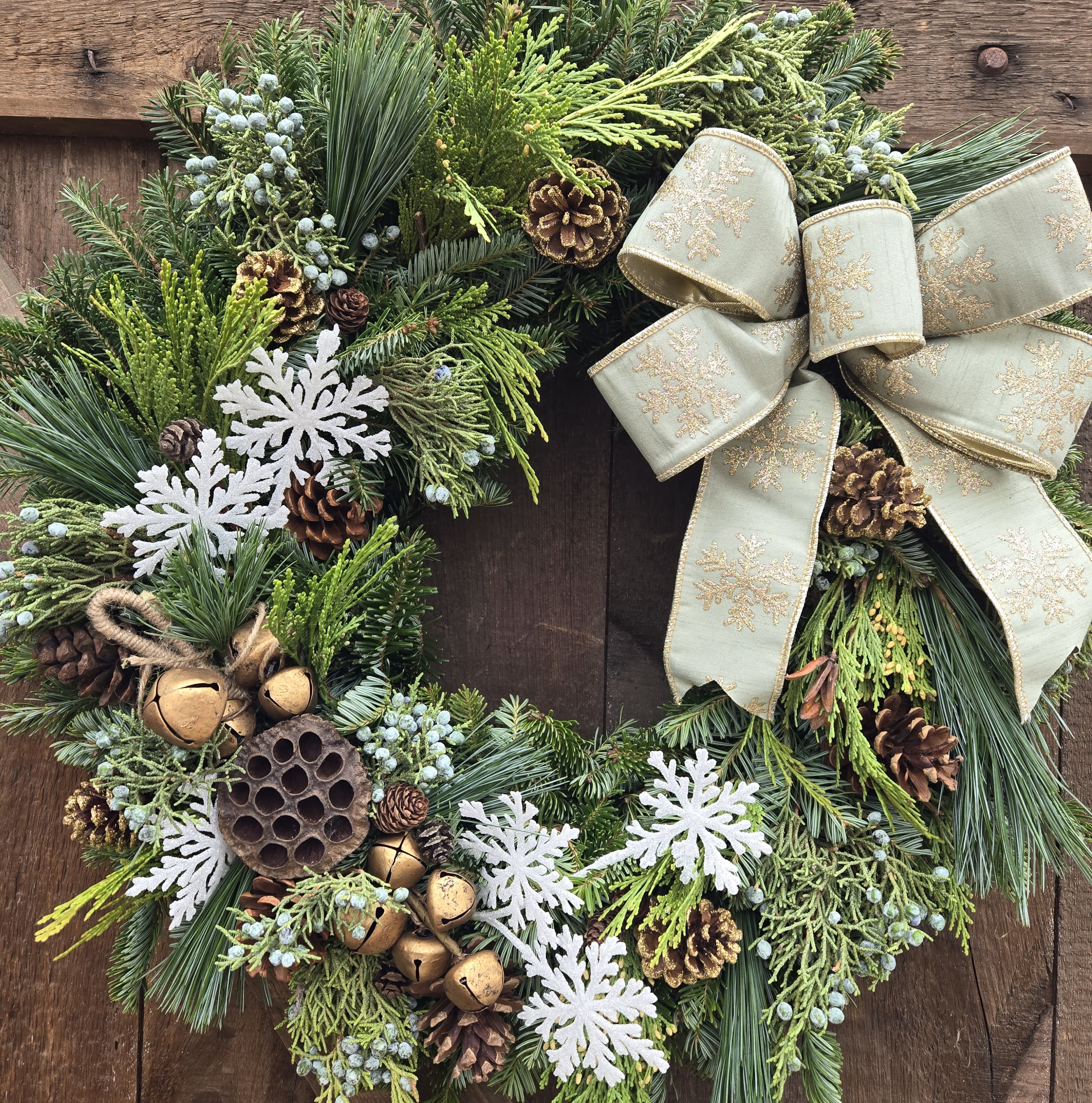 Snowbells Wreath GC-41543 - Sleighbells ring with this winter themed wreath in white and gold. Featuring antique gold style bells and white snowflakes along with a sage green bow. Ribbons and accents may vary from what is pictured. 