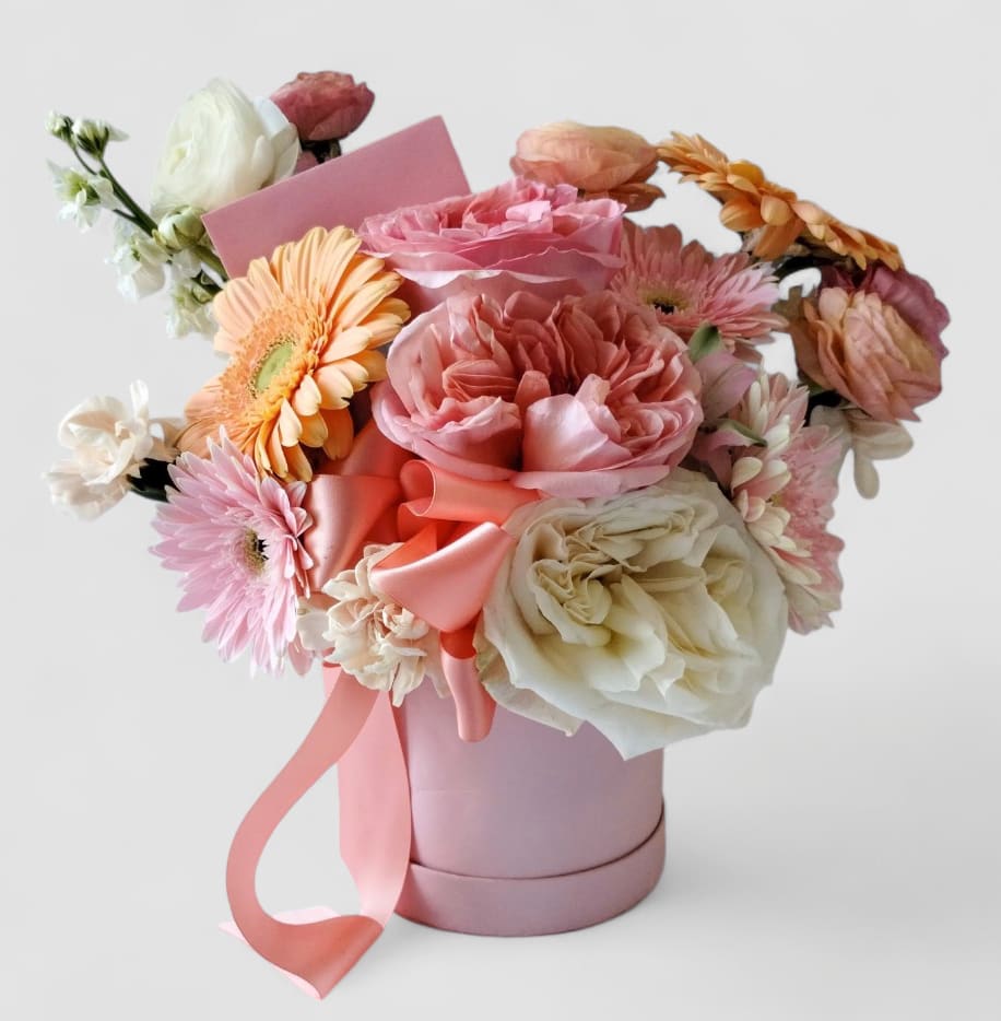 Blush Blossoms Flower Box - Send this beautiful hat box bouquet today to show them you are thinking of them with it's lovely mix of blush colored blossoms of that day roses orchids and so much more arranged in a pretty pink hat box. Perfect to send for every occasion. All bouquets are always made extra special and unique each and every time. Please visit my beautiful gallery to see my latest designs that I have created for my online customers. Send them happiness today.