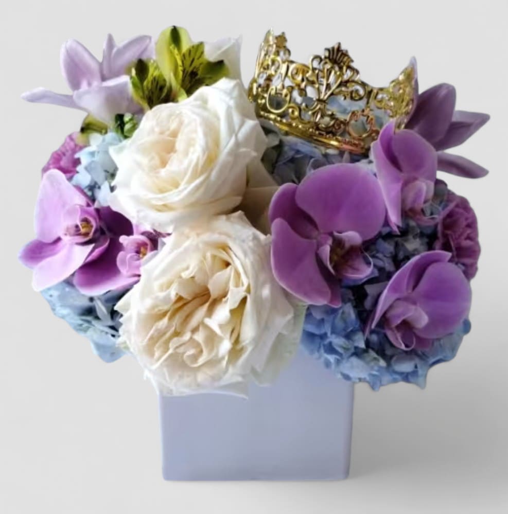 Lavender Blue Beauty Bouquet - Send this beauty today to show them how much you care with it's beautiful lavender orchids and vanilla garden roses adorned with a gold crown and arranged in a beautiful white glass modern vase. Perfect to send for every occasion to send happiness. All bouquets are always made extra special and unique every time. Please visit my gallery which showcases my latest flower designs. Send happiness.