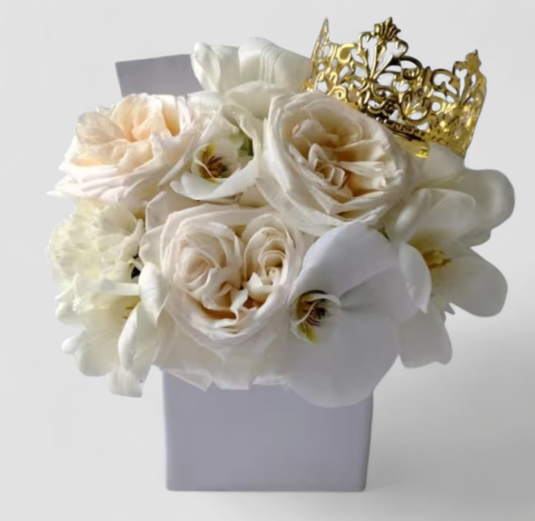 Vanilla Blossoms Beauty Designer's Choice - Send this pretty beauty today to show them that you are thinking of them with it's lovely vanilla blossoms of that day roses orchids and more arranged in a white modern glass vase adorned with a gold crown. Perfect to send today for every occasion. All bouquets are always made extra special and unique each and every time. Please visit my beautiful gallery to see my latest designs that I have created for my online customers. Send them happiness today.