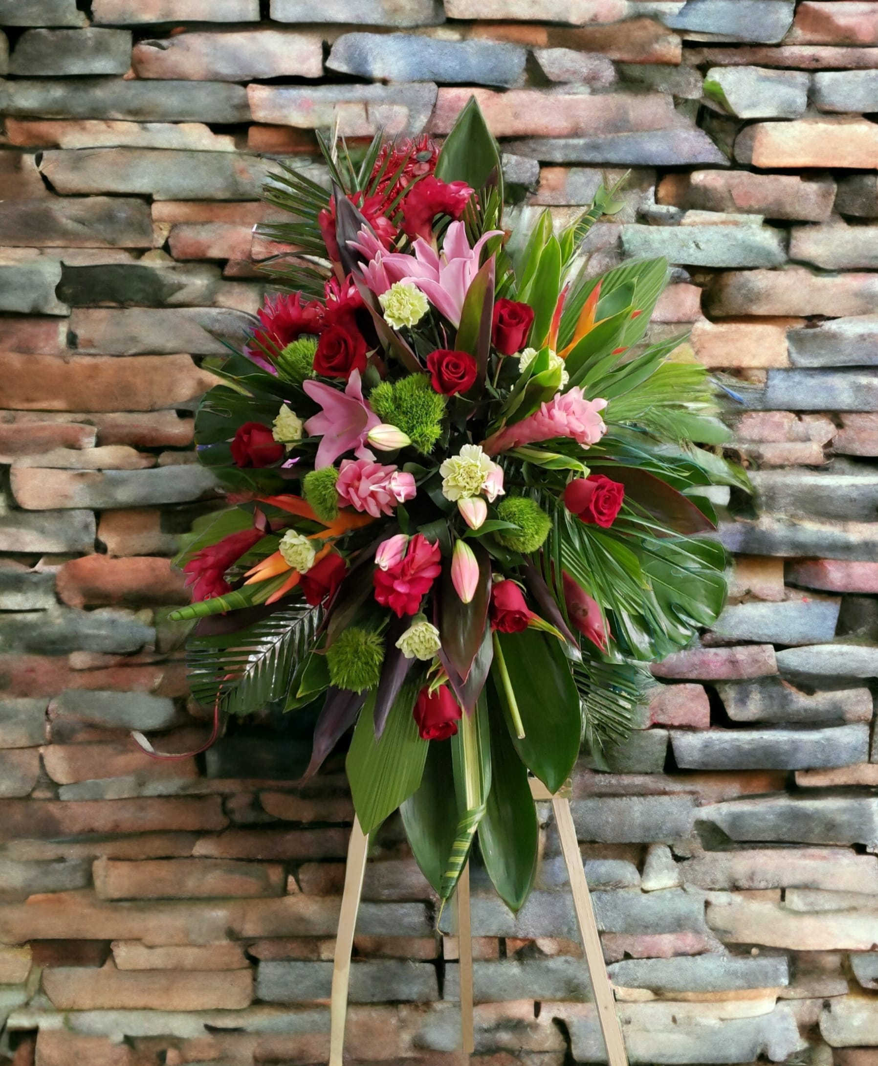 Eternal Paradise - Offer thoughtful condolences with a standing spray of lilies, tropicals, roses, cartations. Hand arranged by our florist with the freshest pink flowers and seasonal greens. 