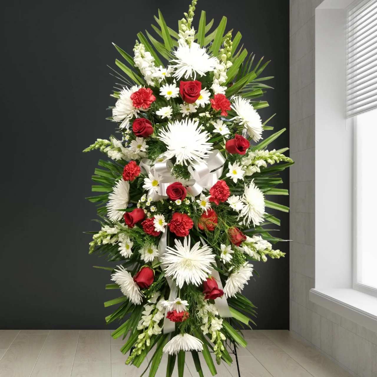 Red &amp; White Sympathy Standing Spray - With red flowers that symbolize love and white flowers that symbolize reverence, this beautifully crafted standing spray conveys all the love and sympathy you feel deep in your heart.  Standing spray arrangement of fresh red and white flowers such as roses, carnations and more.  Appropriate for family, friends and business associates to send directly to the funeral home