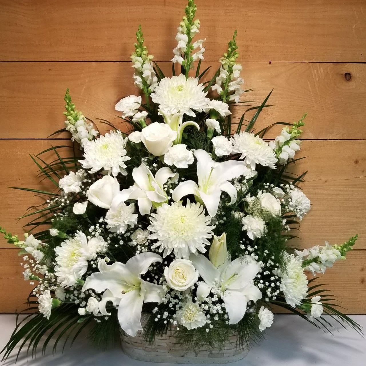 Peaceful Passage - Peaceful Passage S3-4975 Let this exquisite bouquet deliver your sincere condolences at this time of loss and sadness. An always-appropriate mixed bouquet of white roses, carnations, snapdragons, football chrysanthemums, LA hybrid lilies, and million star gypsophelia plus an assortment of lush greens comes hand-arranged in a charming white wood chip basket 