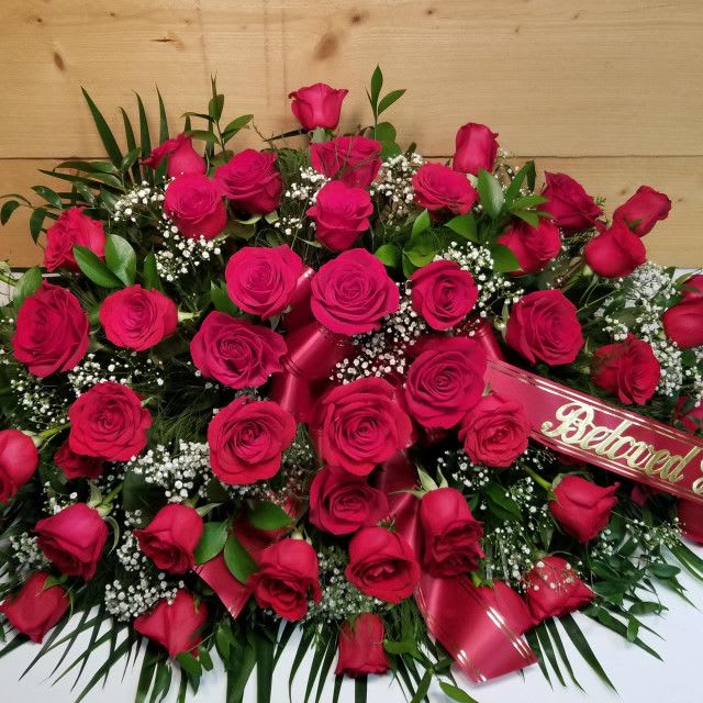 Red Rose Half Casket Spray - The Red Rose Half Casket Spray by Savilles Country Florist is a stunning tribute to your loved ones memory.  An absolutely dazzling display of four dozen premium red roses accented with baby's breath, greens and a ribbon bow.  You may request the color of bow in order comments located in the delivery information section of our online checkout.