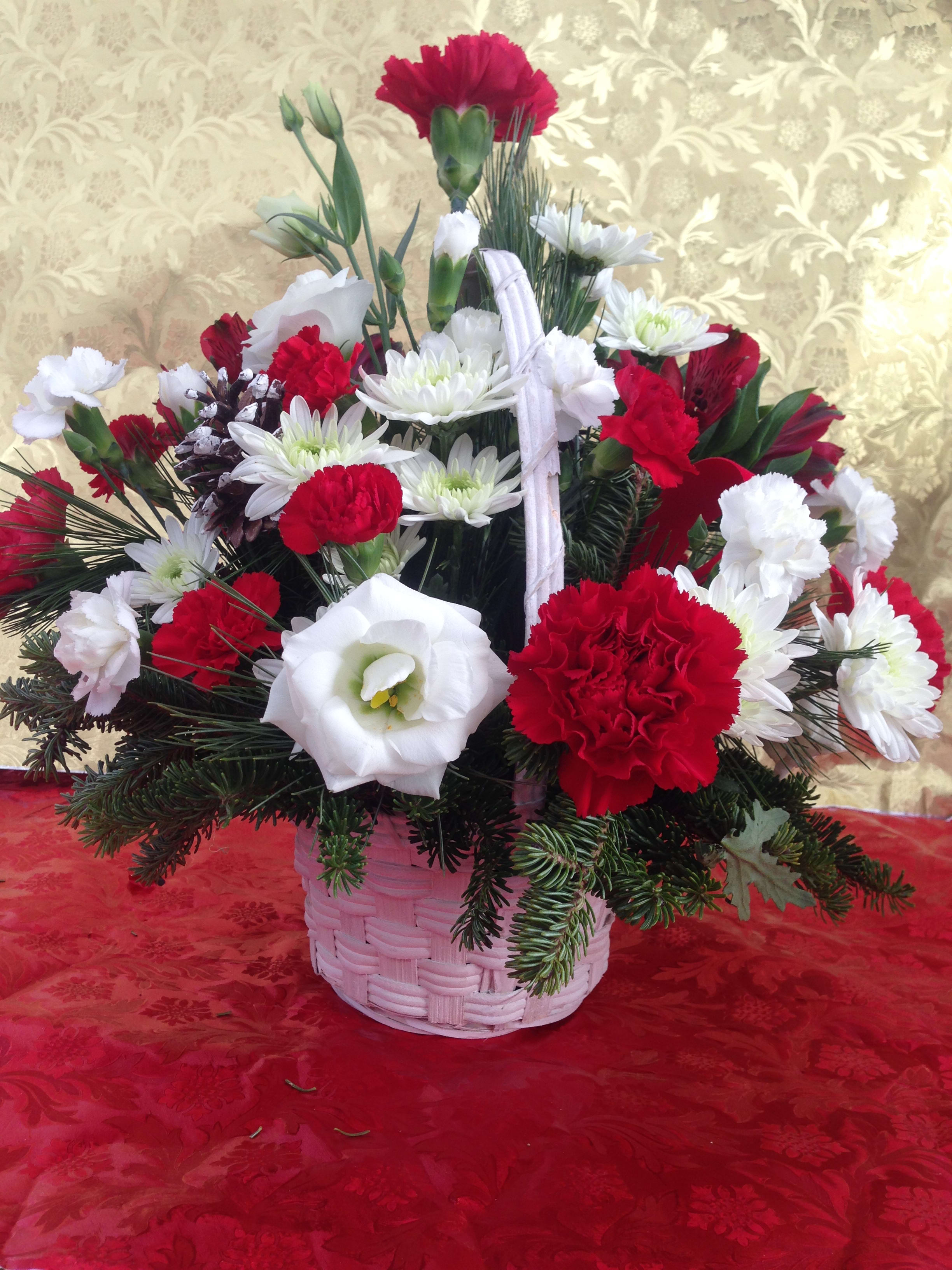 Basket of Cheer - A festive holiday cheer basket full of greens, flowers, pine cones and ribbons.