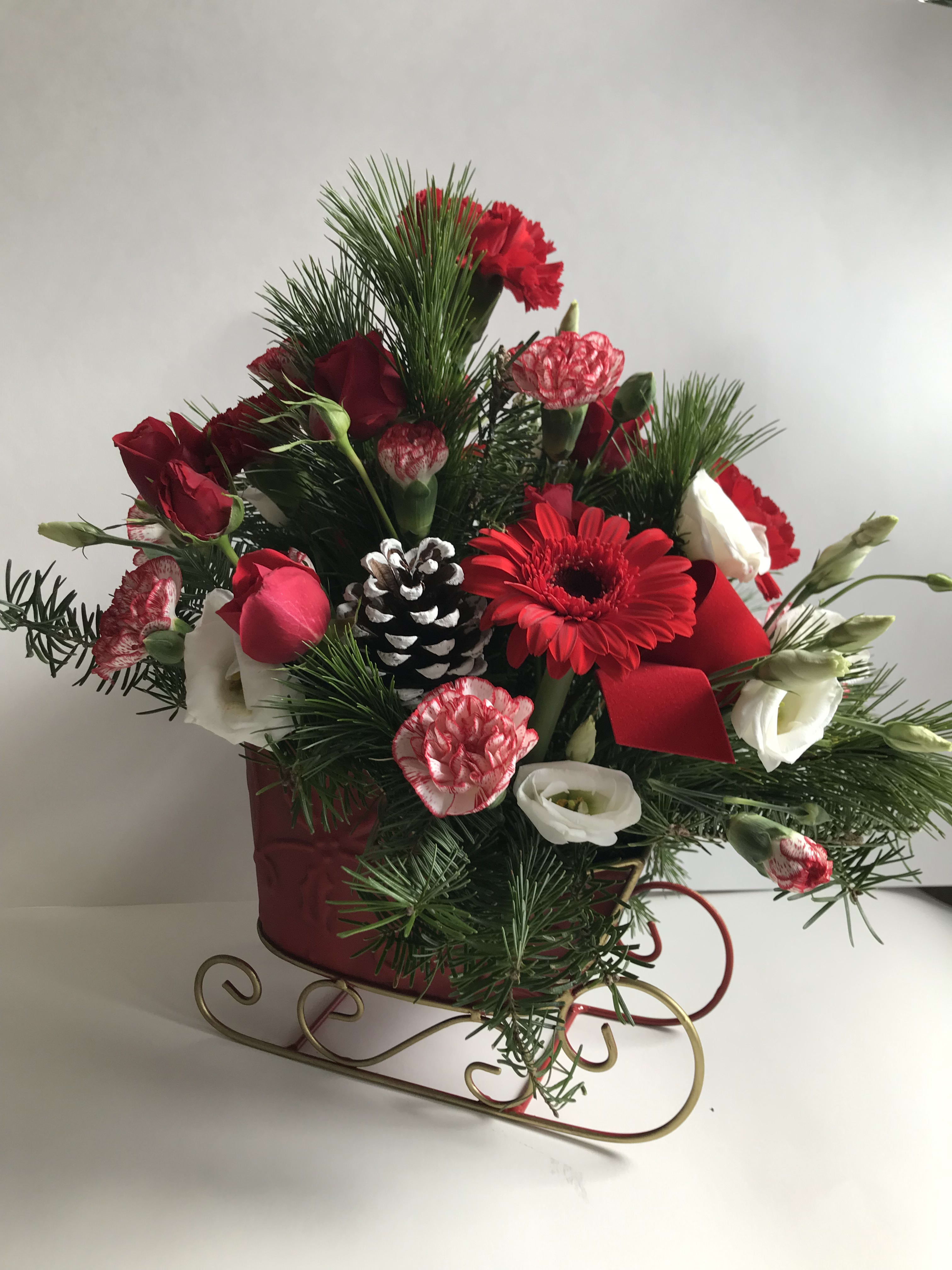 Santa Sleigh  - Festive sleigh with an array of greens, red and white flowers, pine cones and ribbons for your holiday decor or table