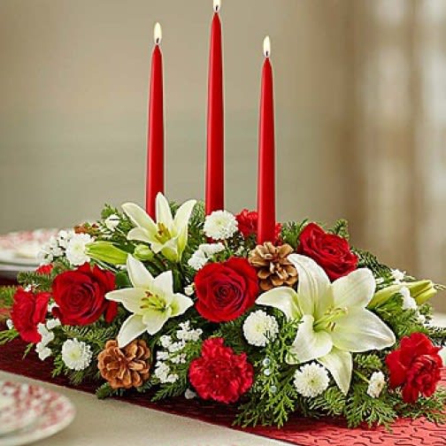 Holiday Centerpiece - This beautiful centerpiece will compliment any holiday table. Three long taper candles are surrounded by lovely white lilies and ruby red roses touched with pine cones and filled with evergreens its a fragrant array of flowers. 
