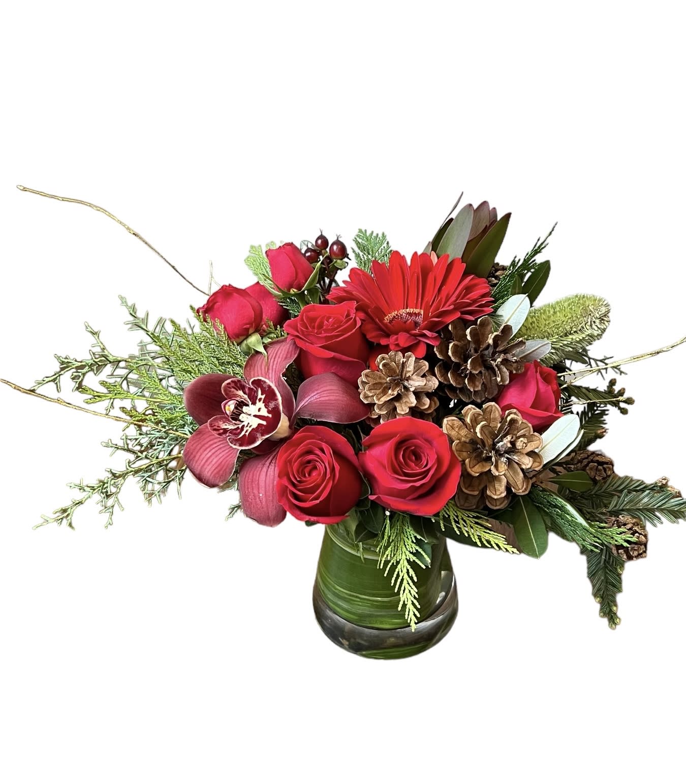 Holiday Magic - Red roses, red spray roses, red gerbera daisy, red berries, red cymbidium orchid, pinecones and Christmas greens designed in a glass vase. 