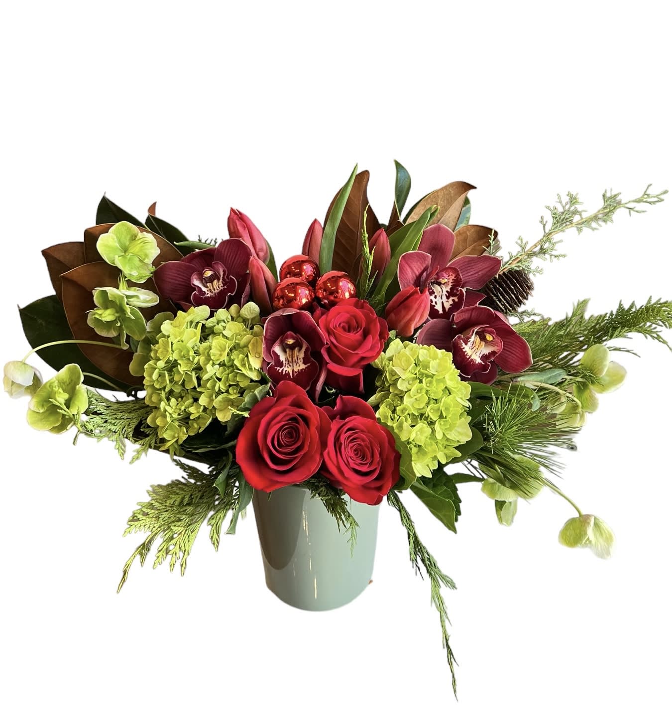 Holiday Cheers - Red rose, green hydrangea, red orchids, red tulips, hellebore, and Christmas greens designed in a green glass vase.