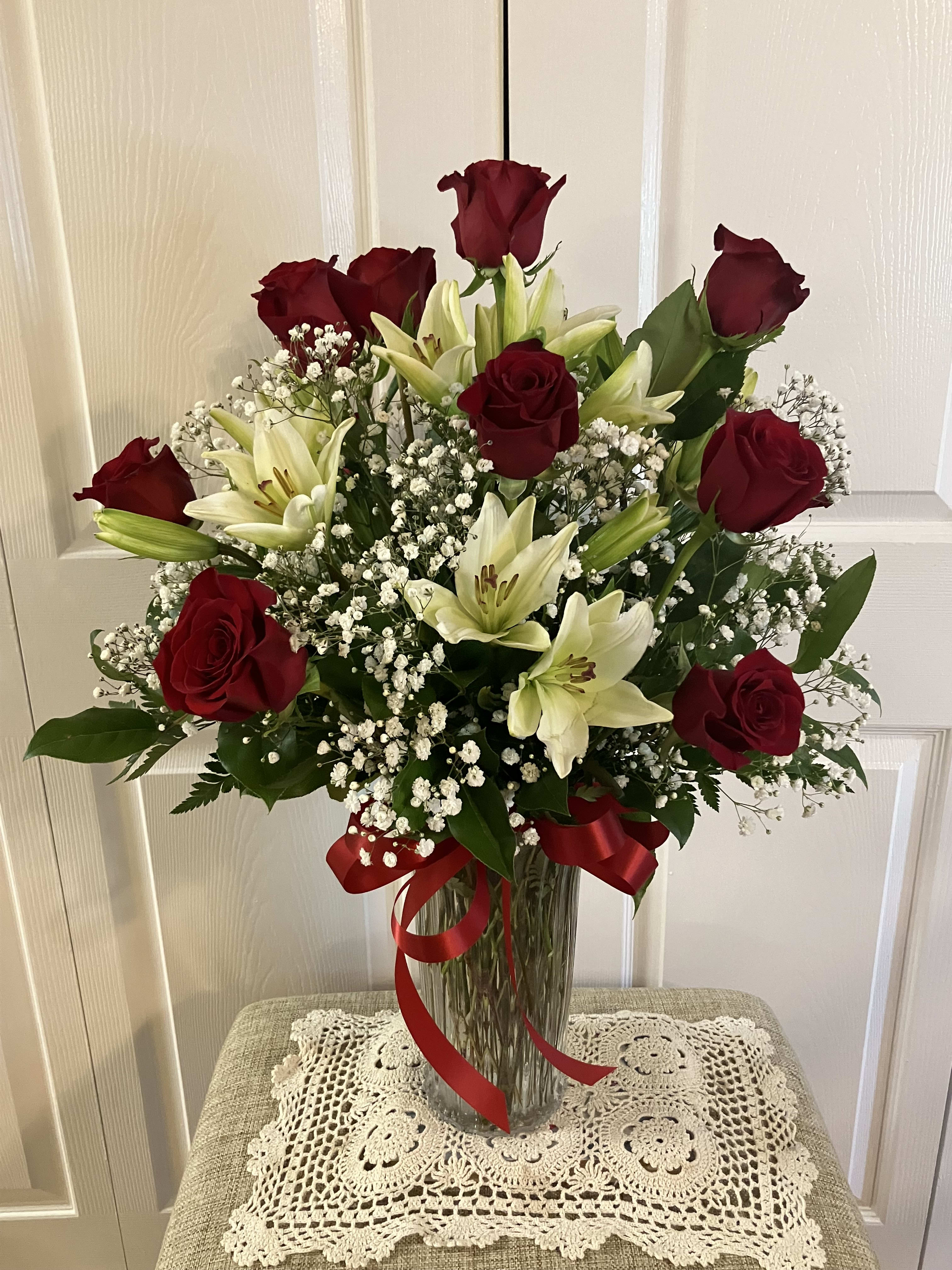 Deluxe Dozen - A dozen red roses complimented with white Lilies and Baby's Breath.