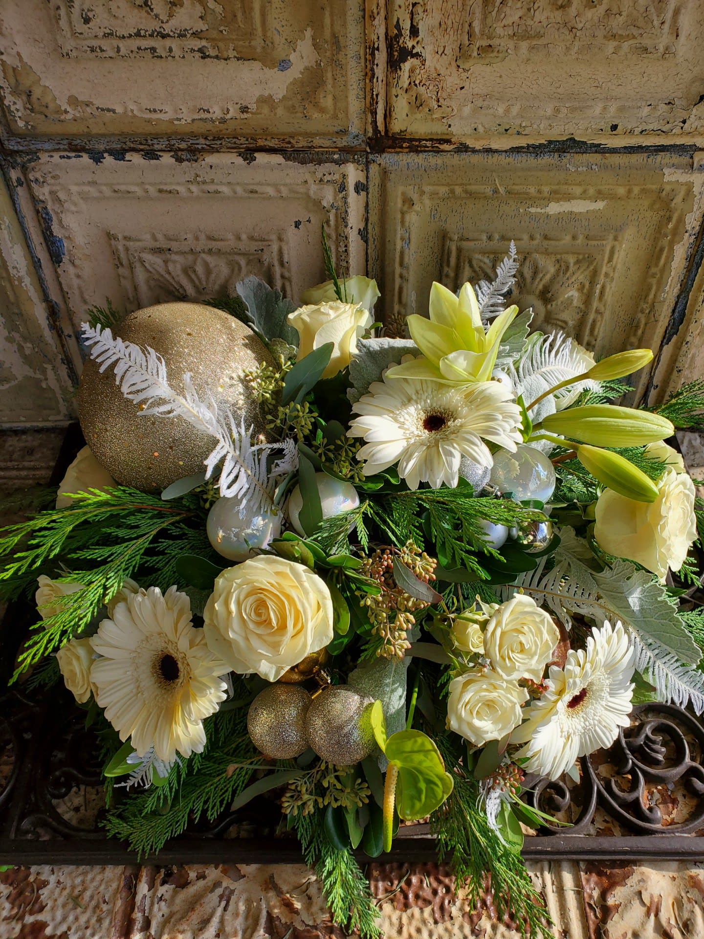 Sarah Jessica Parker - A lovely, neutral holiday arrangement of lilies, gerbera daisies, roses and spray roses, cedar, seeded eucalyptus, anthurium, dusty miller, bleached umbrella fern, and assorted Christmas ornaments.